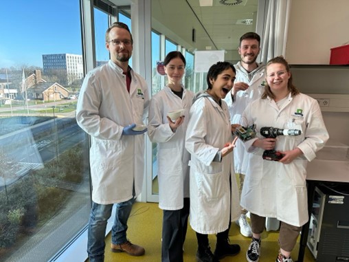 Five young people in lab coats pose with their equipment.