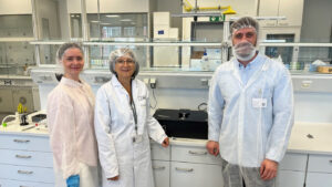 Two young researchers from university Ulm together with a representative from Seeberger pose in the lab in front of the photonics prototypes.